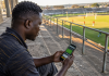 Man checks a football betting app on his smartphone from the stadium stands